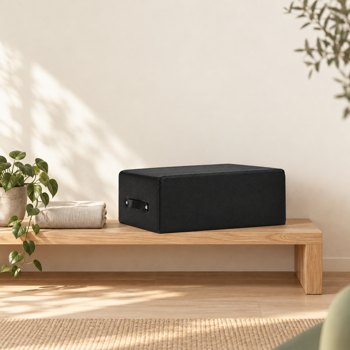 Box Pilates noire rangée sur une étagère basse en chêne à côté d'une serviette en lin